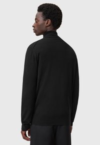Sort pullovertrøje med høj krave, lange ærmer og ribstrikkede manchetter. Blød tekstur med en glat overflade. Minimalistisk design.