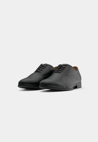 Pair of black leather formal lace-up shoes with rounded toes on a plain white background, angled slightly to the right.