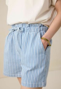Shorts rayés bleu clair avec une taille élastique, détail de cordon de serrage et poches latérales. Associés à un haut uni de couleur neutre.