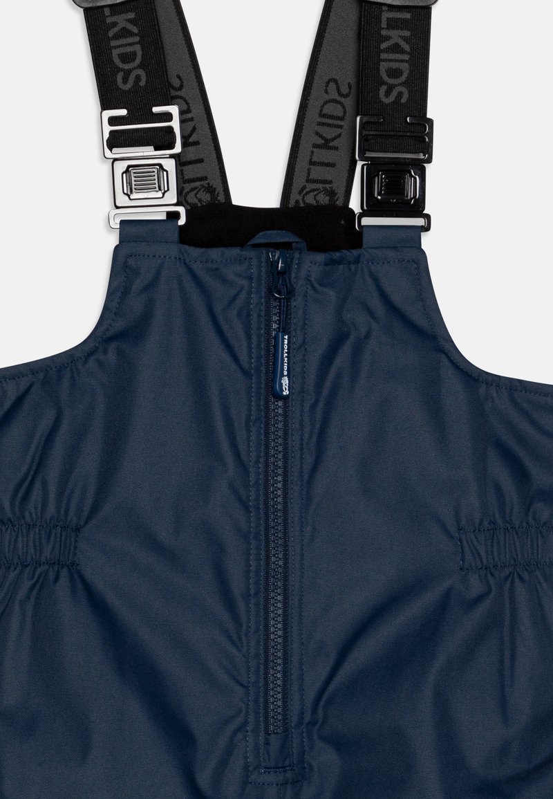 Marineblaue Schneehosen mit verstellbaren schwarzen Trägern und silbernem Zubehör. Sie verfügen über einen Frontreißverschluss und elastische Seiten für eine optimale Passform.