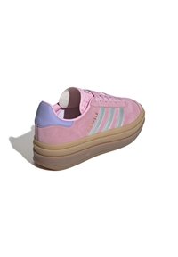 Pink suede sneaker with three silver stripes, purple heel accent, and a beige rubber sole. Features a rounded toe and cushioned collar.