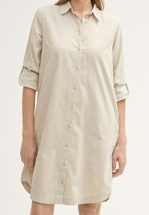 Beige knoopshirtjurk met opgerolde mouwen, voorzien van een kraag, zachte stoftextuur en een rechte snit, die boven de knieën valt.