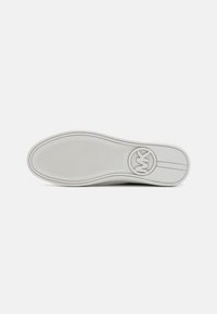 Suela de zapato de goma blanca con un patrón texturizado y un logo circular en el talón, con un acabado suave y detalles sutiles de contorno.