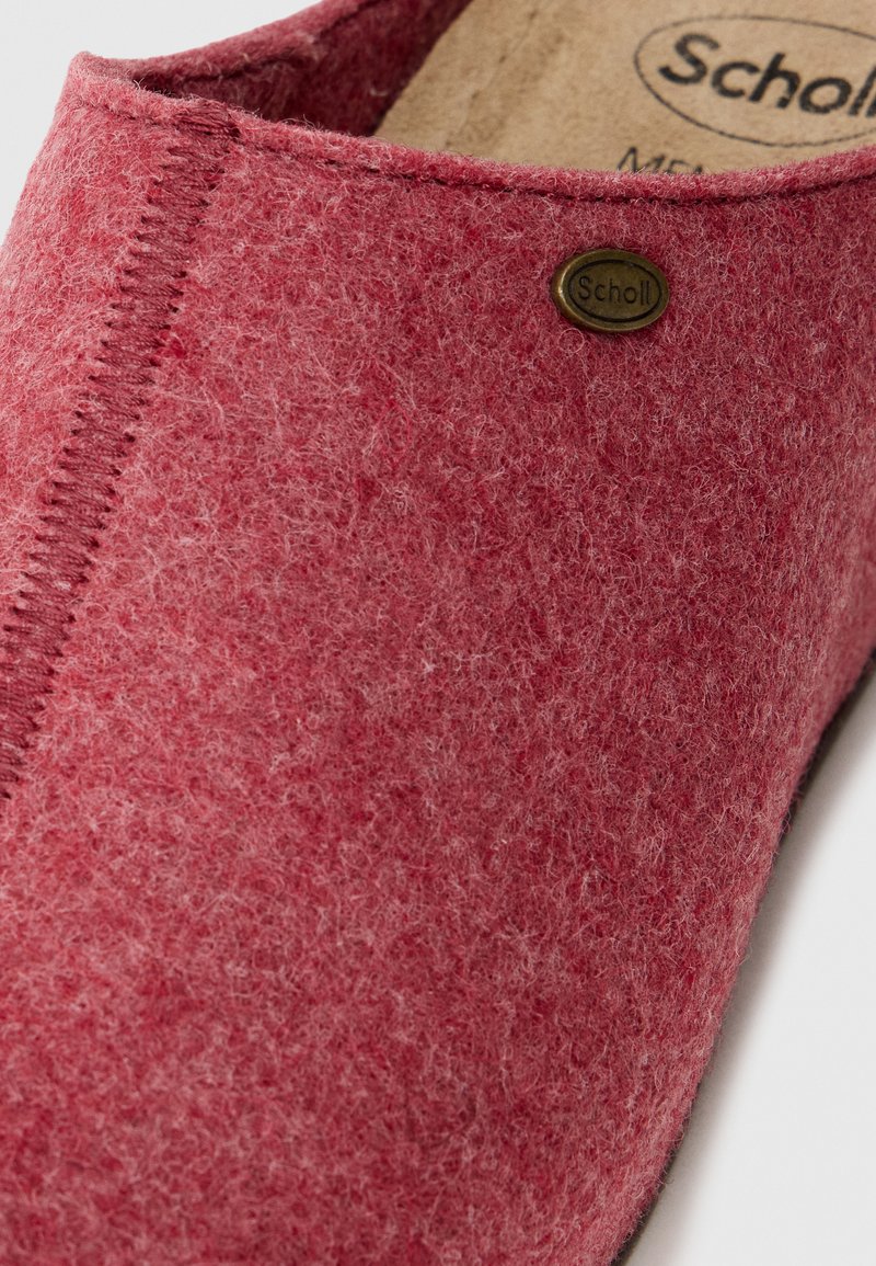 Scarpa slip-on rossa in feltro con design arrotondato. Presenta cuciture visibili e un piccolo logo in ottone. Texture morbida.
