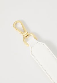 Bracelet en cuir blanc avec clip en métal doré, présentant une texture lisse et des coutures propres le long des bords. Le clip comprend un mécanisme à ressort.