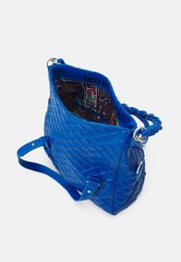 Blau gestepptes Handtasche mit einer strukturierten Oberfläche, geräumigem Innenraum mit einem bunten gemusterten Futter und einem geflochtenen Griff.