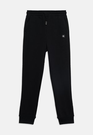 Czarne wąskie spodnie dresowe typu jogger z elastycznym pasem, sznurkiem, bocznymi kieszeniami, ściągaczami przy nogawkach i małym logo Calvin Klein na lewym udzie.