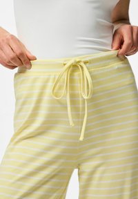 Geel gestreepte sweatpants met een trekkoord in de taille, voorzien van witte horizontale strepen en een zachte, textuurrijke stof.