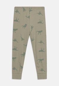 Leggings en tissu doux et côtelé avec un motif de dinosaure vert et de lion. Taille élastique ; coupe ajustée ; fond beige clair.