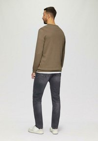 Long-sleeve olive green sweatshirt with a rounded neckline, paired with dark gray jeans and white sneakers. Simple design, soft texture.