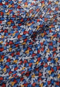 Tissu multicolore avec un motif de cœur abstrait vibrant. Texture légère et douce avec des plis et un fond bleu clair.
