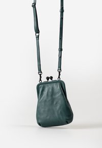 Borsa a mano in pelle turchese con una forma strutturata, dotata di chiusura a scatto e di una tracolla rimovibile per indossarla a tracolla o sulla spalla.