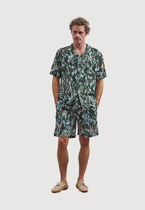 Short-sleeve button-up shirt and matching shorts in green, blue, and beige abstract pattern; lightweight fabric; worn with beige slip-on shoes.