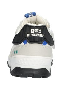 Sneaker in pelle bianca con accenti neri, dettagli blu e verdi, retro testurizzato e un distintivo tallone con il testo "Be Yourself".