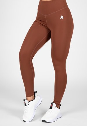 Bruine hoger uitgesneden leggings van rekbare stof, met een gladde textuur en een wit logo accent op de dij.
