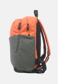 Rugzak met oranje bovenstof, zwarte mesh zijkant en groene onderzak. Beschikt over twee ritssluitingen en verstelbare schouderbanden.