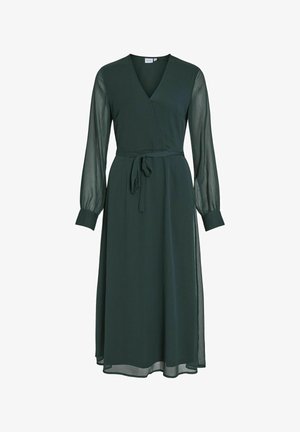 Donkergroene wikkeljurk met lange doorschijnende mouwen, v-hals en een strik middel. Vloeiende stof reikt tot halverwege het onderbeen en heeft een gladde textuur.