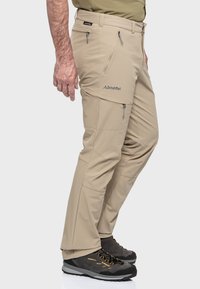 Beige Outdoor-Hosen mit Reißverschluss-Taschen, taillierter Passform und verstärkten Nähten. Das Material ist leicht und atmungsaktiv, geeignet für aktive Nutzung.