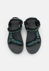 Sandales sportives noires et vertes en teinte avec des sangles ajustables à motif, semelle texturée et design ouvert à l'avant. Matériau respirant et léger.