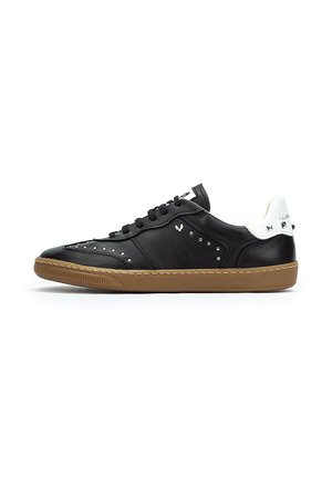 Zapatillas de cuero negro con una textura suave, adornadas con tachuelas plateadas en el costado, una tapa de talón blanca y una suela de goma.