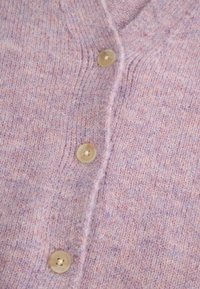Kardigan z miękkiego dzianinowego materiału w jasnym odcieniu fioletu z różowymi drobinkami, wykończony okrągłymi, jasnymi guzikami z przodu.