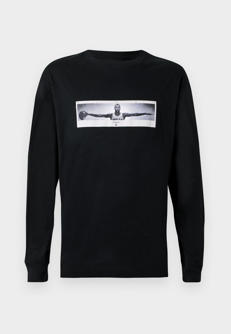 Schwarzes Langarm-T-Shirt mit einem Frontdruck, der eine Figur in einem schwarz-weißen Foto mit ausgestreckten Armen zeigt; Rundhalsausschnitt-Design.