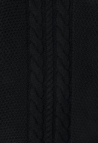 Schwarzer Strickstoff mit einem strukturierten Muster auf beiden Seiten eines erhöhten, geflochtenen zentralen Designs. Glattes, dichtes Garn mit filigranen Details.