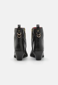Botas de tobillo de cuero negro con un patrón de serpiente texturizado, punta redondeada, detalles dorados y un tacón bajo. Cierre con doble cremallera en los laterales.