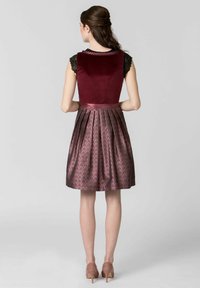Burgundy velvet dress with a fitted bodice, lace cap sleeves, and a pleated skirt in a rich patterned fabric, finished with a satin waistband.