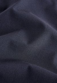 Tissu bleu marine avec une texture lisse, présentant des plis subtils et un éclat doux. Le matériau semble léger et flexible.