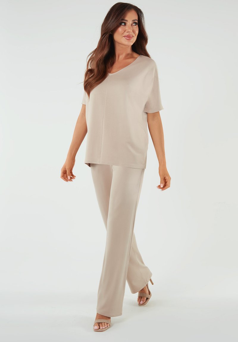 Beżowy dwuczęściowy strój z luźnym, krótkim topem i dopasowanymi spodniami. Gładka faktura, prosty krój i minimalistyczny design.