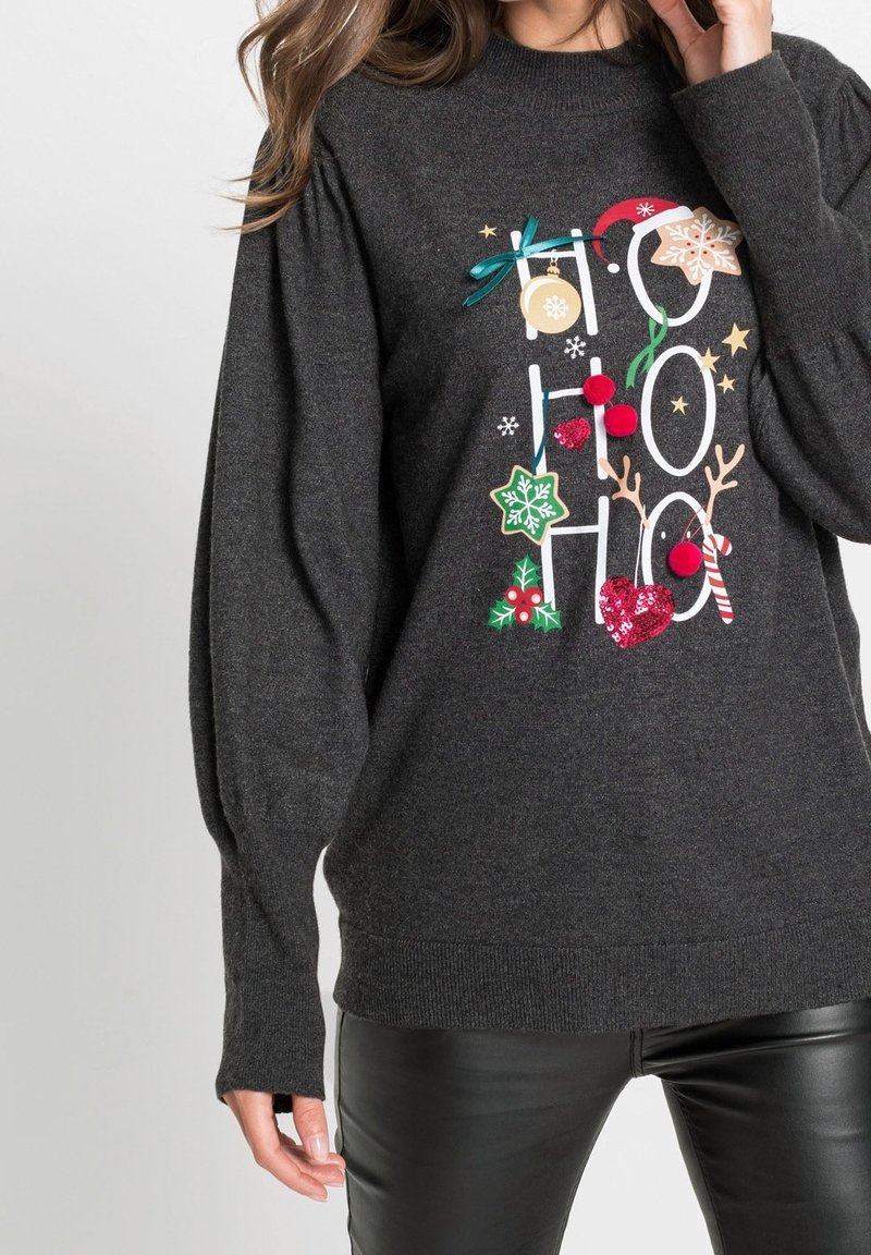 Suéter gris oscuro con un gráfico festivo de "Ho Ho Ho". Presenta adornos coloridos como pompones y acentos de purpurina, así como puños acanalados.