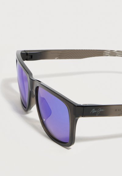 Μαύρα ορθογώνια γυαλιά ηλίου με αντανακλαστικούς μπλε φακούς, υφασμένες γκρι βραχίονες και λογότυπο "Maui Jim" στο πλάι.