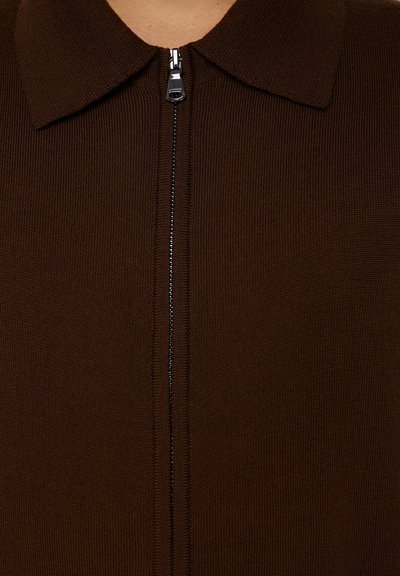 Maglione marrone a costine con zip e colletto. Presenta una zip centrale con accessori in argento e un tessuto texturizzato. Design semplice, senza motivi.