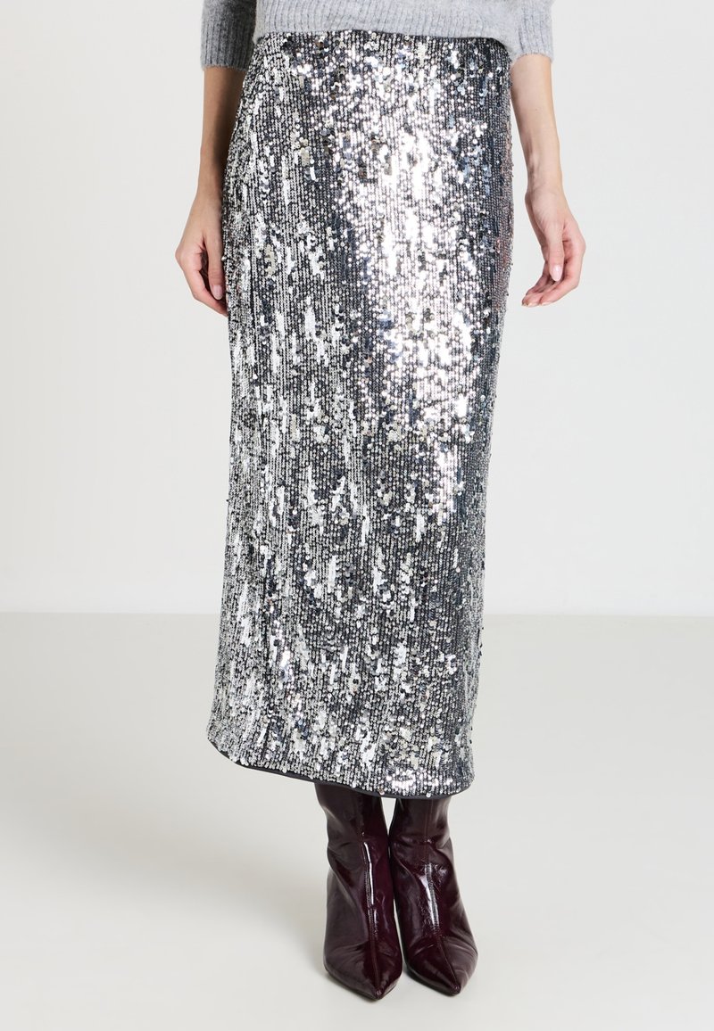 Gonna maxi argento con paillettes, a taglio dritto, texture lucida e motivo sottile, abbinata a stivali in pelle bordeaux al ginocchio.