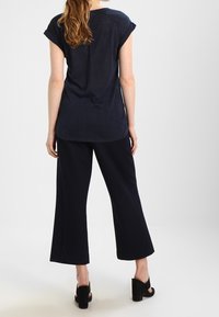 Navy blue short-sleeve top with a loose fit, paired with wide-leg navy trousers. Shoes with a chunky heel, black with a smooth texture.