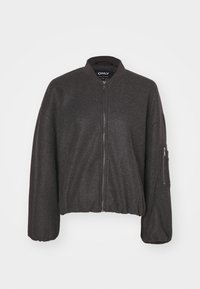 Tamno siva bomber jakna s patent zatvaračem, rebrastim okovratnikom i elastičnim strukom. Sadrži prevelike rukave i zip džep na lijevoj ruci.