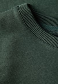 Tessuto di cotone verde scuro con un collo a girocollo a coste. La trama è liscia con una finitura uniforme e sottile. Nessun motivo o dettaglio visibile.