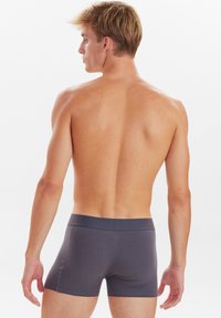 Boxer in cotone grigio da uomo con una texture morbida e liscia, vita elastica e design minimalista, visti da dietro.