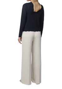 Granatowy dzianinowy sweter z długim rękawem o prążkowanej strukturze, w zestawie z kremowymi spodniami o szerokich nogawkach, prezentującymi gładkie wykończenie materiału.