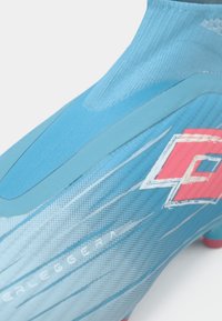 Kratki prikaz svijetloplavih nogometnih kopački s ružičastim šiljcima, bijelim točkastim uzorcima i crvenim Lotto logotipom sa strane.