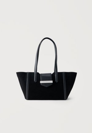 Sac cabas en daim noir avec une forme structurée, de longues poignées en cuir et un rabat avant avec une plaque de marque argentée.