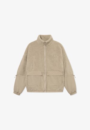 Chaqueta de piel sintética beige con cuello alto, cierre frontal, dos bolsillos en el pecho y dos grandes bolsillos inferiores, con puños elásticos y una textura suave.