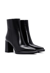Bottes noires en cuir à cheville avec un bout pointu et un talon carré épais. Texture lisse et design minimaliste. Pas de matériel ou d'embellissements visibles.