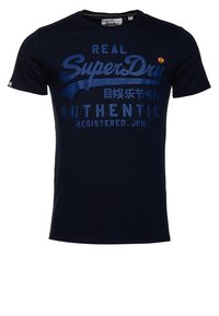 Granatowa, krótko rękawowa koszulka z niebieskim napisem "Real SuperDry Authentic Registered. JPN" oraz japońskimi znakami na przodzie.