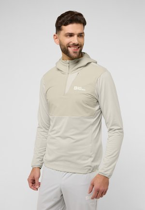 Pullover con cappuccio di un beige chiaro realizzato in un tessuto liscio e elastico. Presenta un collo a zip, maniche lunghe e un design a blocchi di colore distintivo.