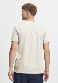 Beige kortærmet t-shirt med rund halsudskæring, enkelt design, blød tekstur og lige skæring. Ingen synlige mønstre eller grafik.