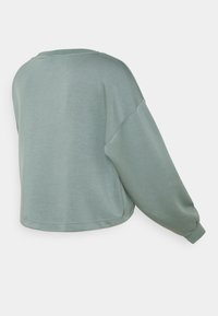 Felpa verde tagliata, con una texture morbida, maniche larghe e scollo arrotondato. Dettagli con cuciture sull'orlo e sui polsini.