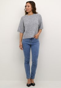 Light gray, fuzzy sweater with short sleeves and a round neckline, paired with high-waisted blue jeans and black pointed-toe flats.