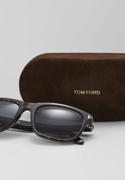 Tom Ford sunglasses with a tortoiseshell frame, dark lenses, gold accents, and a matching brown suede case featuring a gold logo.